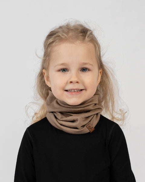 Kids merino wool neck gaiter in beige worn as scarf, lightweight and comfortable for everyday use.