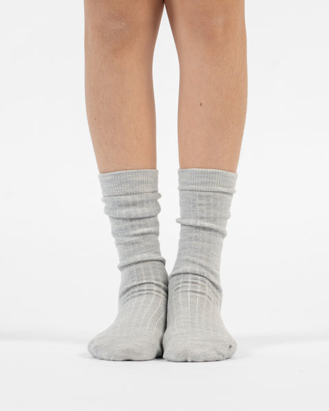 A front view of lower legs standing flat, modeling light gray ribbed merino crew socks.