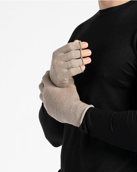 A person wearing a black long-sleeved shirt is shown from the chest up, putting on creamy beige fingerless gloves. The background is white.