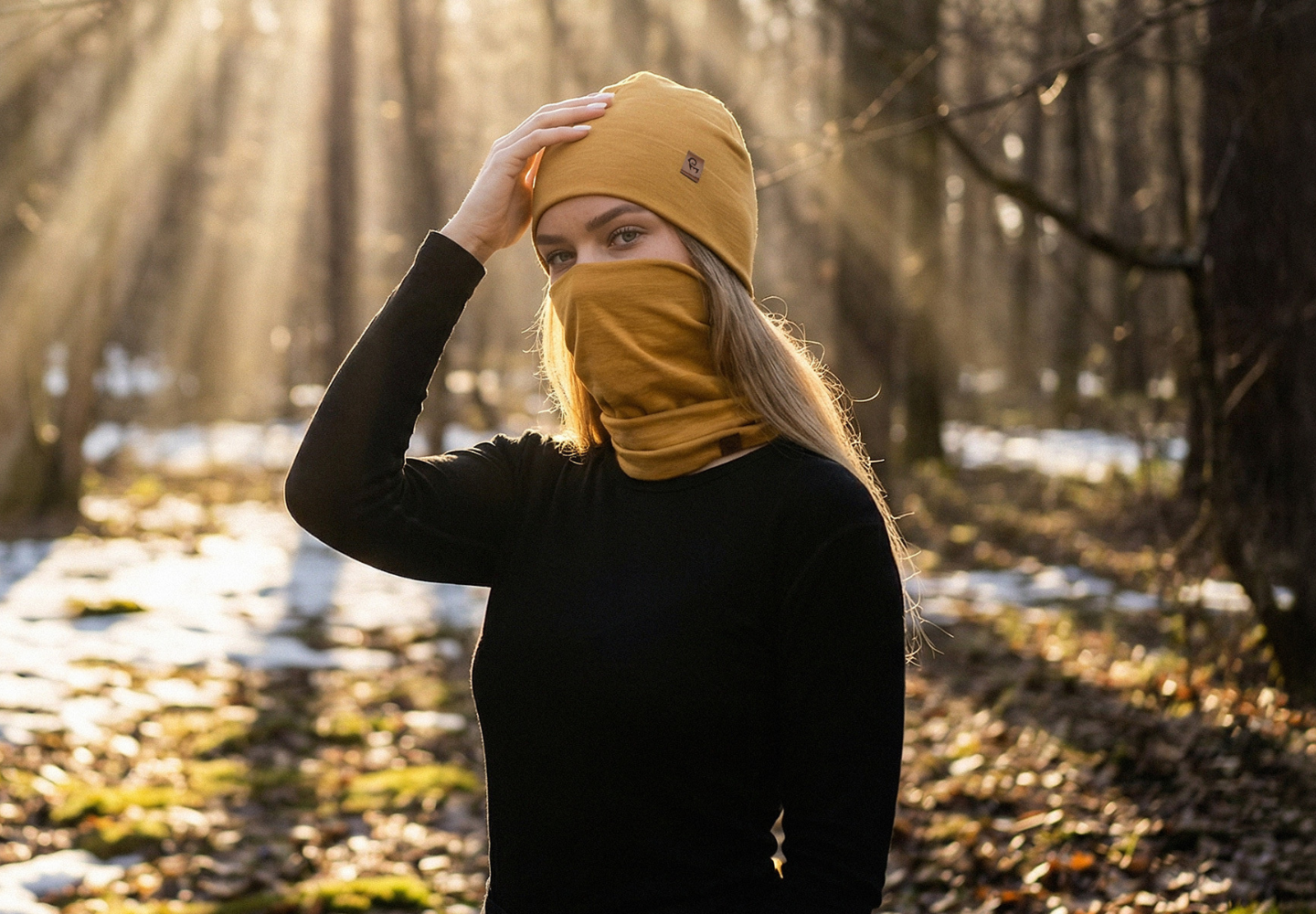 Woman wearing merino wool beanie and neck gaiter outdoors in a forest during cold weather.