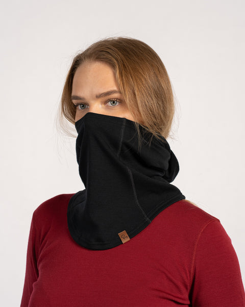 Woman with blonde hair wearing black Merino wool balaclava as a face cover, paired with a red shirt.