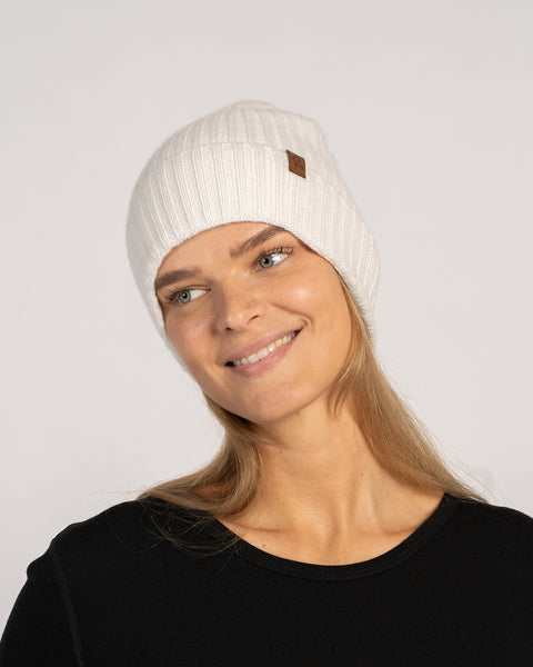 Unisex ribbed beanie in white, knitted from Merino wool and cashmere, shown front view on a model smiling.