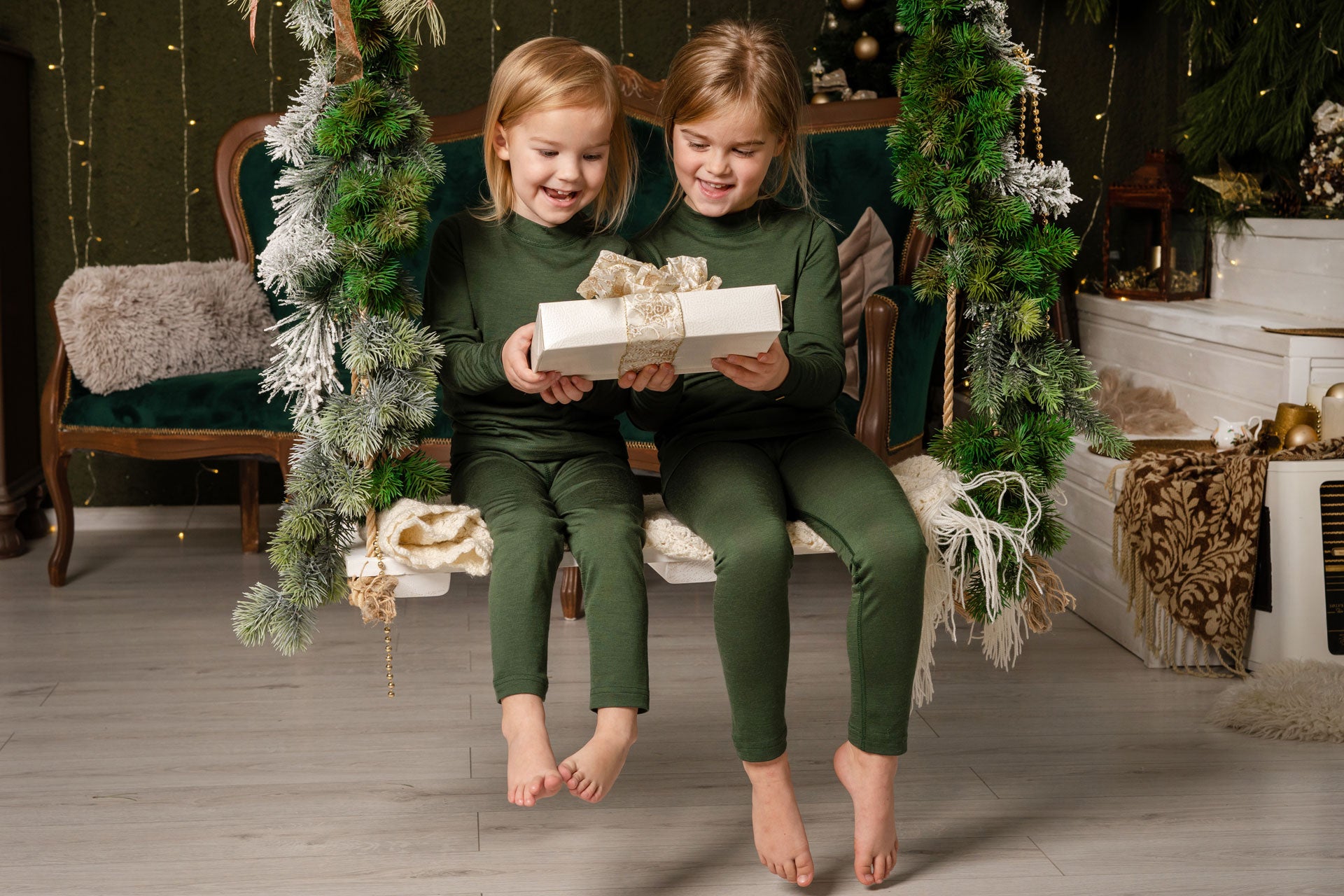 Two little girls holding a chriistmas gift on the swing 