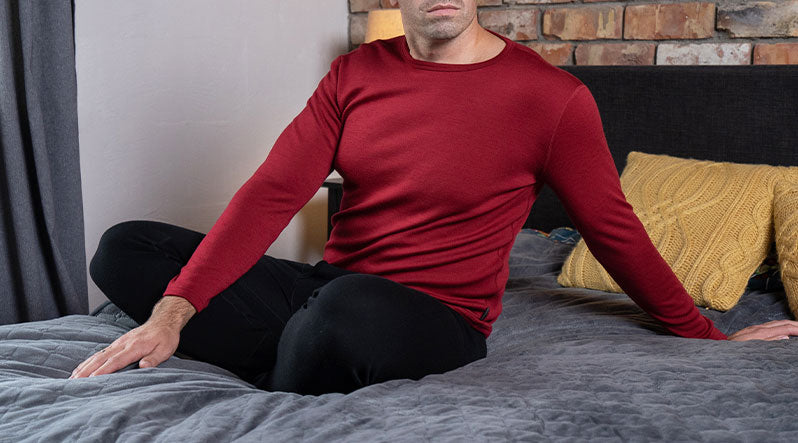Man wearing red Merino wool sweater and sitting on the bed