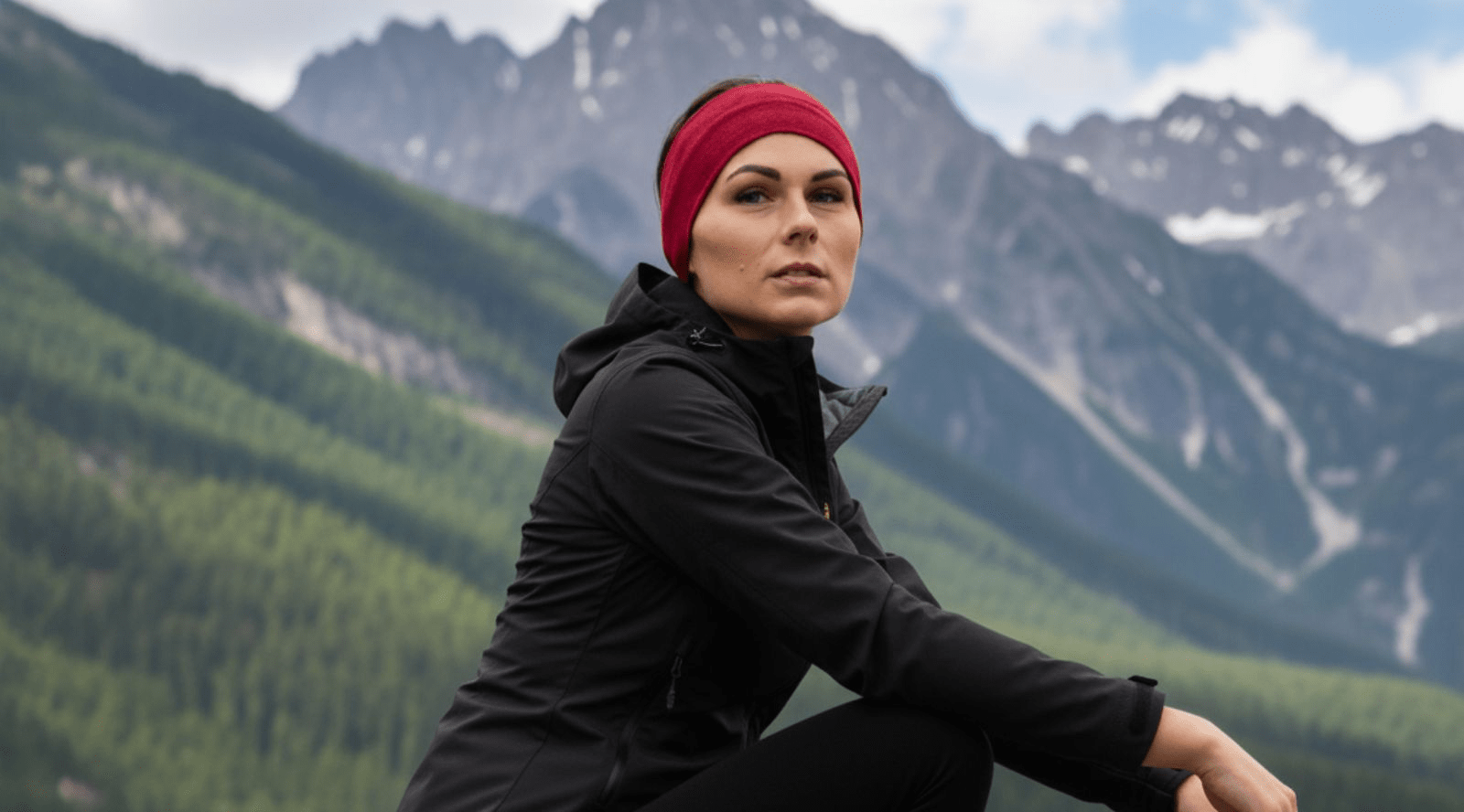 A woman wearing a royal cherry merino wool beanie while it is snowing outside.