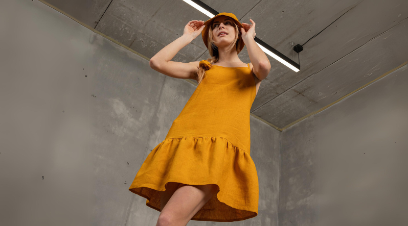 A spicy yellow strap mini dress matched with a bucket hat and a scrunchie hair tie.