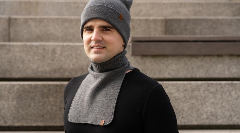A man outdoors wearing black sweater and knitted merino wool dickie in a dark gray color
