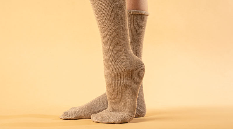 Woman with knitted merino wool socks in creamy beige color.
