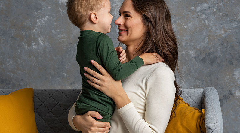 In this photo you can see mom with her son. They are both wearing matching loungewear sets/pajamas made from organic and soft 100% Merino wool. Mother is wearing natural color set and the kid is wearing dark green set.