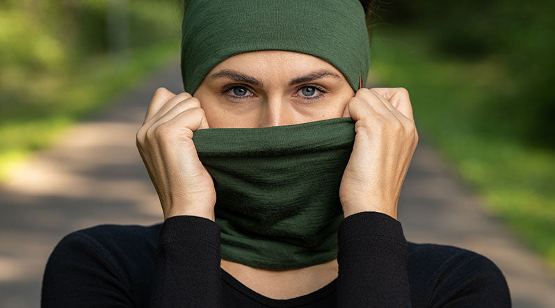 Woman outdoors wearing merino wool gaiter and beanie in a green color.