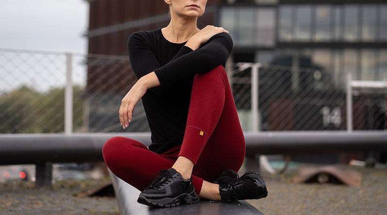 Woman sitting outdoors and wearing red leggings and black long sleeve top