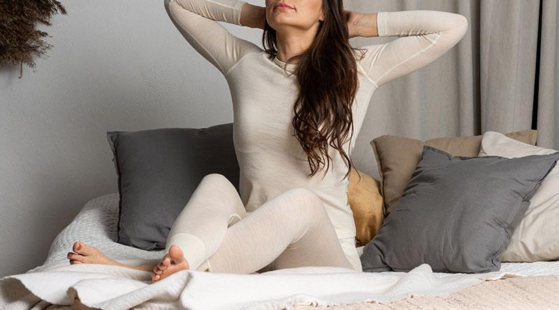 Woman sitting on the bed and wearing natural Merino wool matching set