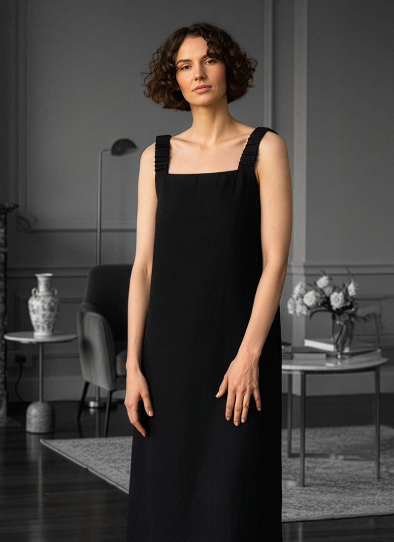 Woman standing in home setting and wearing black dress
