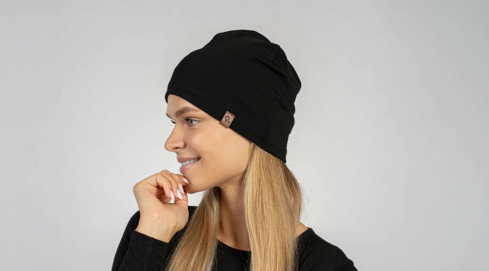 Woman wearing a black beanie against a plain background