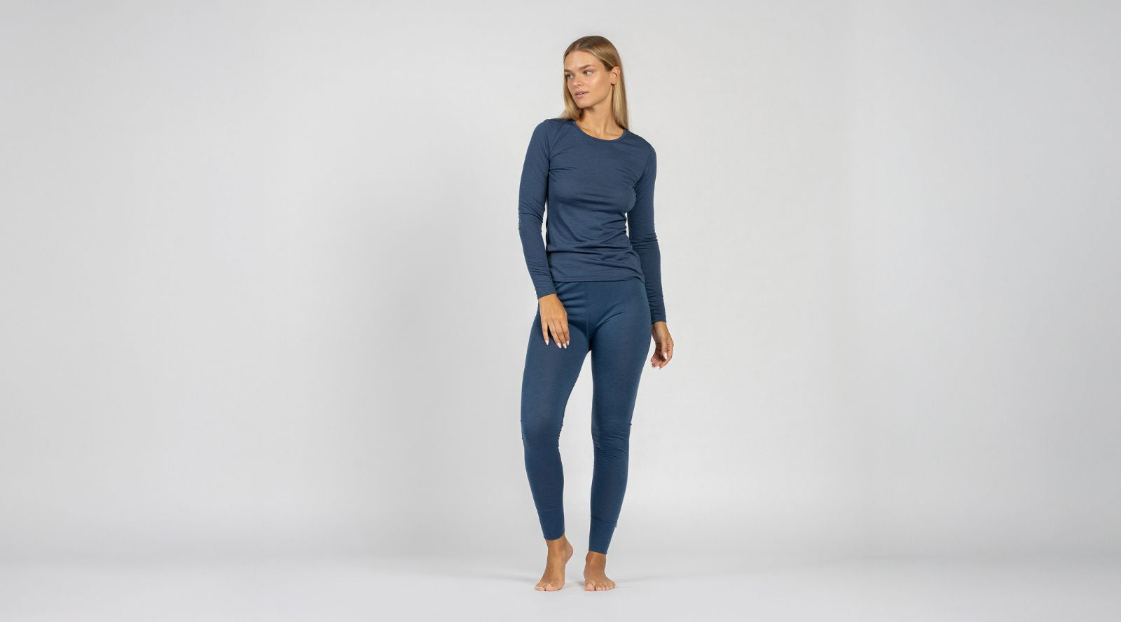 Woman wearing a blue long-sleeve top and leggings on a white background