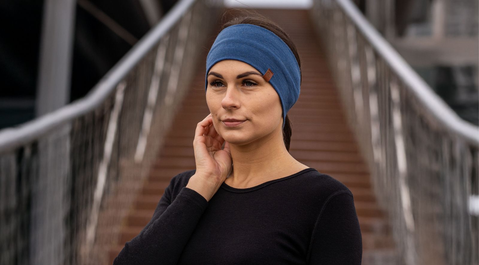 Woman wearing a blue headband outdoors on a wooden bridge