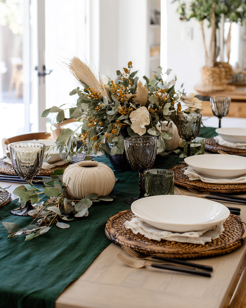 Dark green linen table runner on dining table with fall greenery centerpiece and elegant table setting.