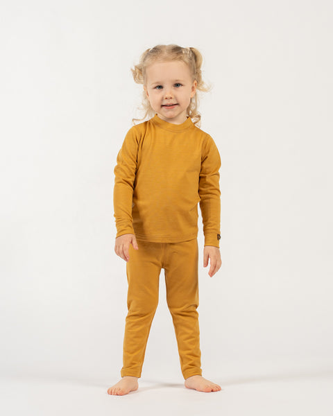 Child wearing a menique merino wool  kids&#39; yellow outfit on a white background