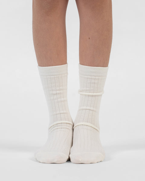 A front view of lower legs standing flat, modeling natural ribbed merino crew socks.