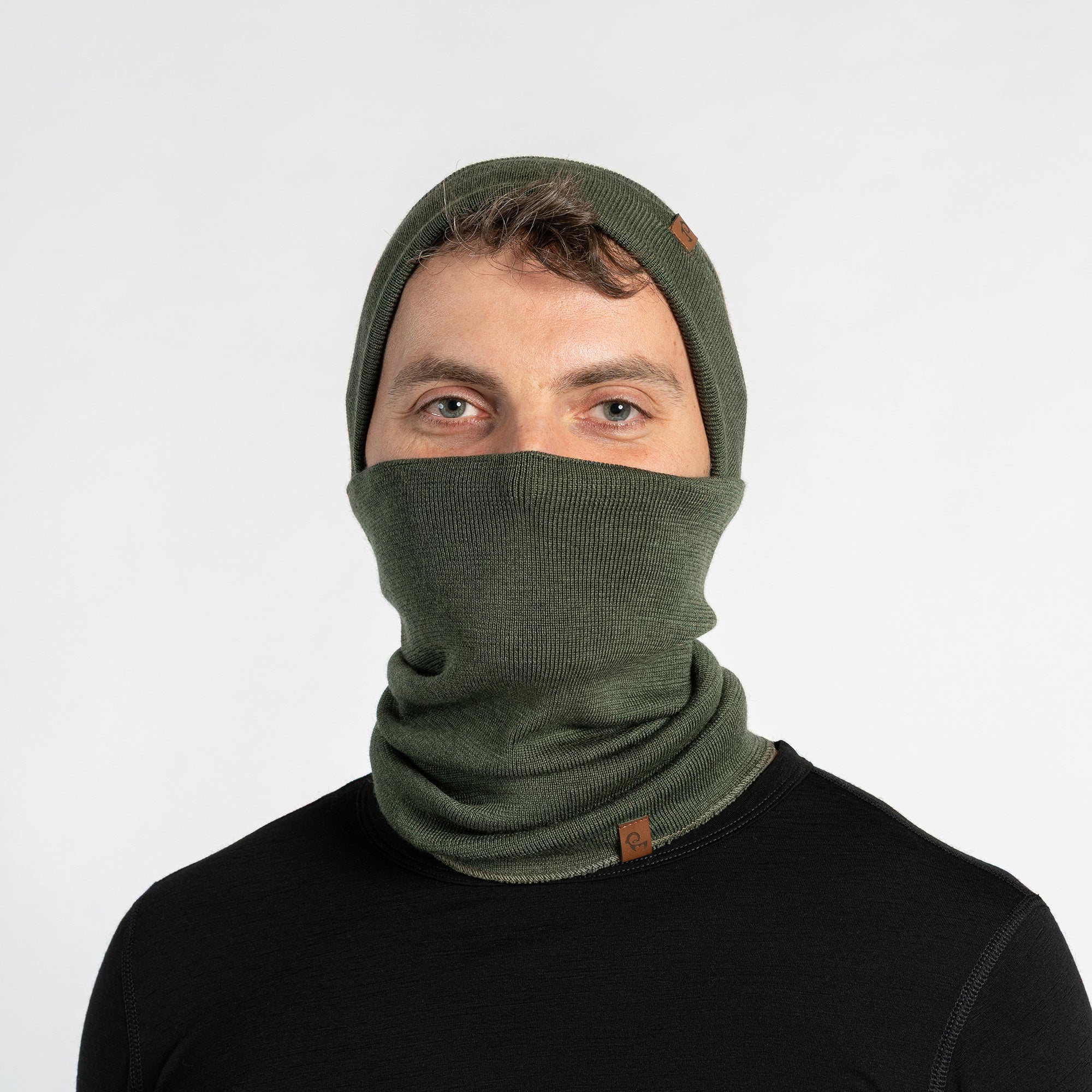 Person wearing a dark gray knit beanie and scarf set on a light gray background