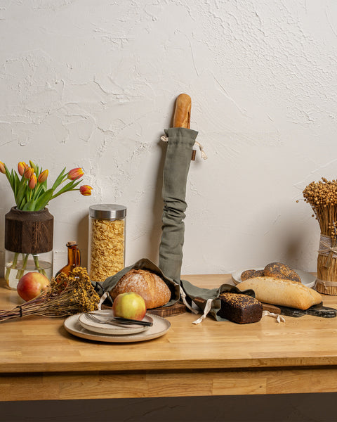 Wooden table with bread, apples, and decorative items against a white wall.