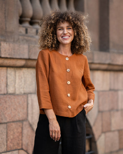 Woman with curly hair wearing almond brown linen jacket Alice and standing in  astreet