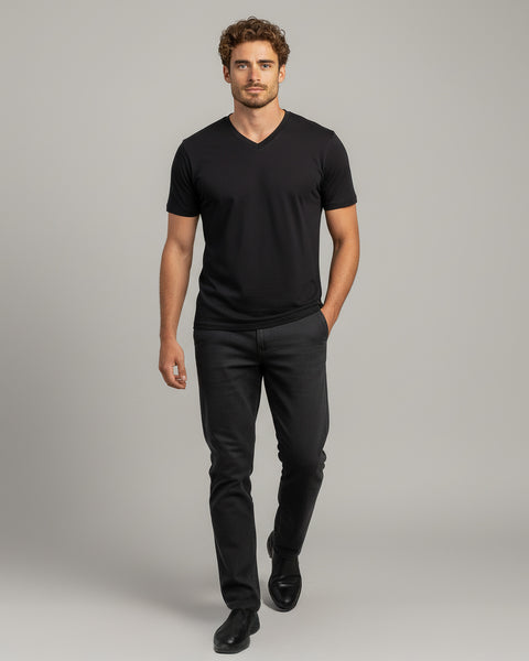 Man wearing a black V-neck t-shirt and black pants on a gray background