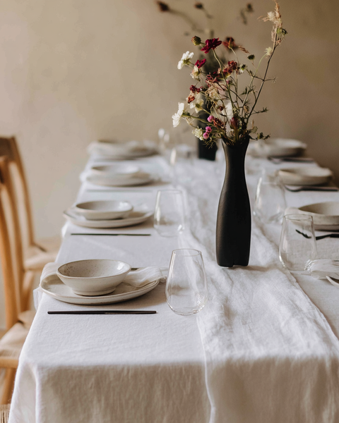 Pure white linen tablecloth with minimalist table setting and ceramic dinnerware for elegant dining.