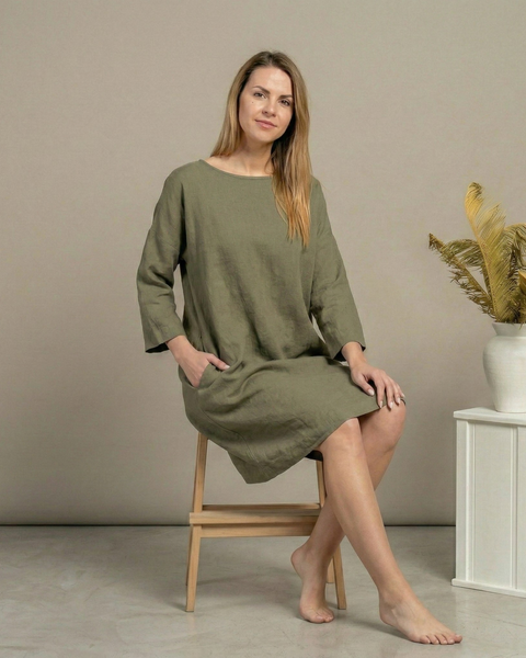 Woman wearing stone green linen dress with relaxed fit and three-quarter sleeves, minimalist natural fabric dress styled in neutral studio setting
