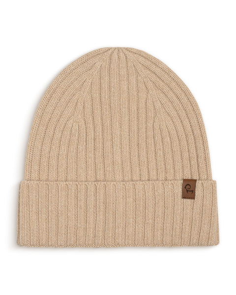 Creamy beige knit beanie with a brown logo tag on a white background