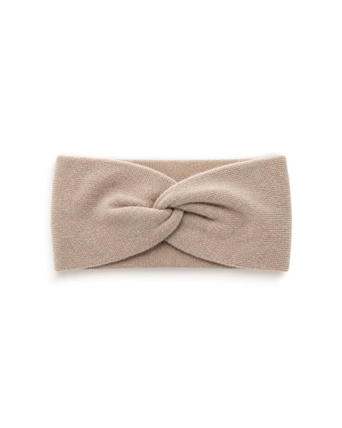 A sand beige knit headband featuring a twisted knot design in the center, displayed flat against a plain white background.
