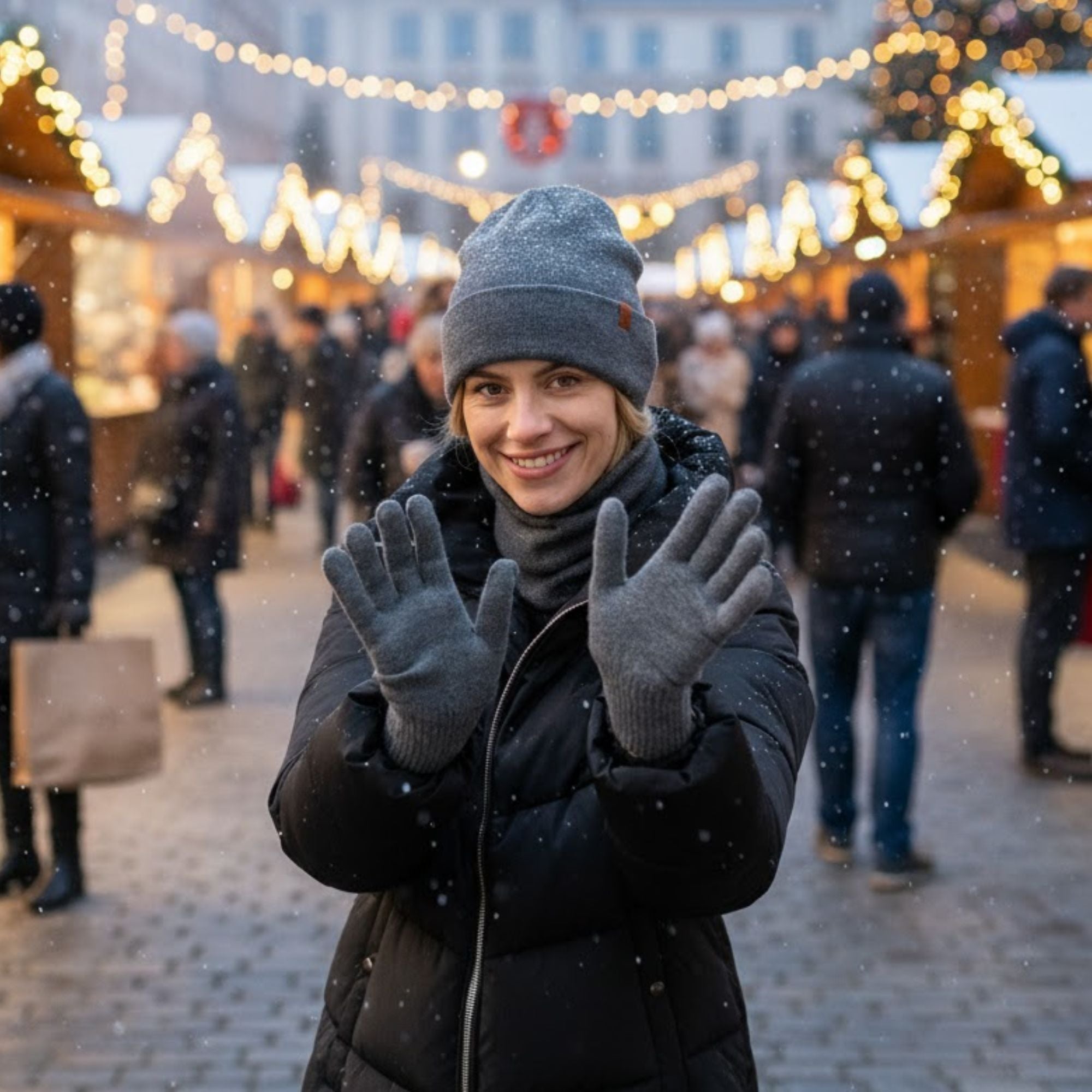 Woman in winter clothing at a festive outdoor market with snow falling.