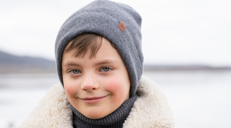 A boy outdoors wearing dark gray knitted merino wool beanie.