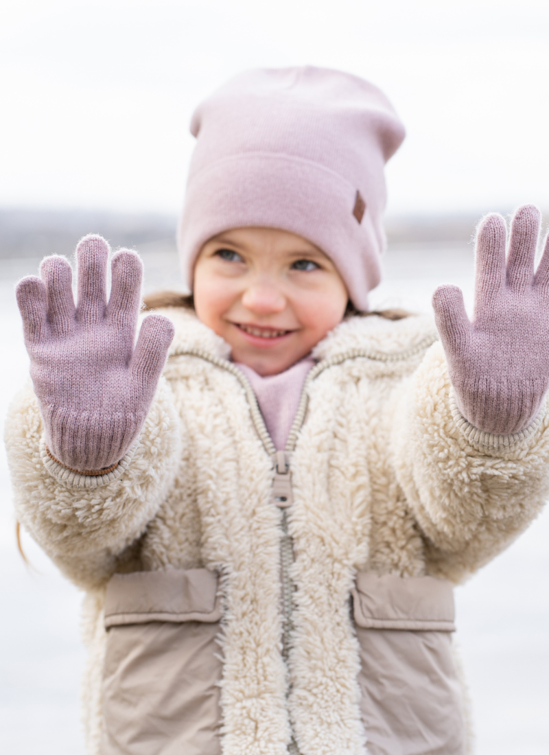 Girl outdoors wearing dust pink knitted merino wool gloves and beanie