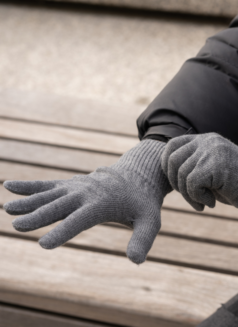Man outdoors with dark gray knitted merino wool gloves.