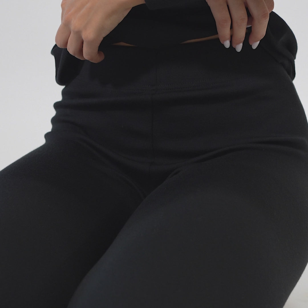 Video of woman slowly taking off her clothing and showing merino wool sport bra in black color.