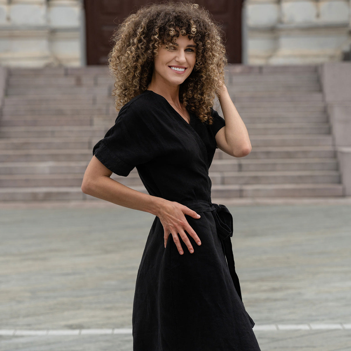 Woman outside in the city posing with a pure black linen dress eliana.
