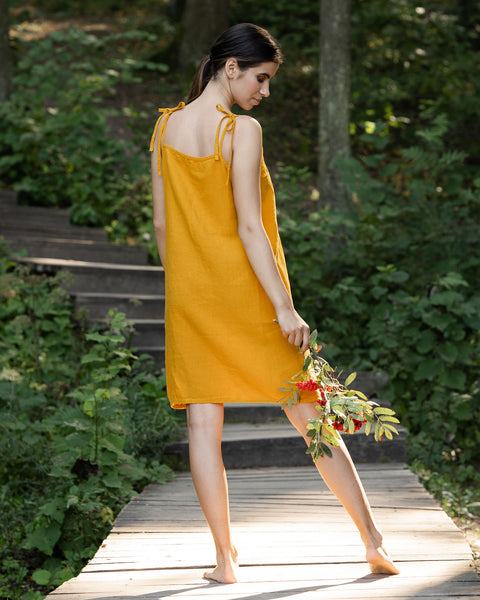 Young beautiful woman showing her back while wearing yellow linen dress
