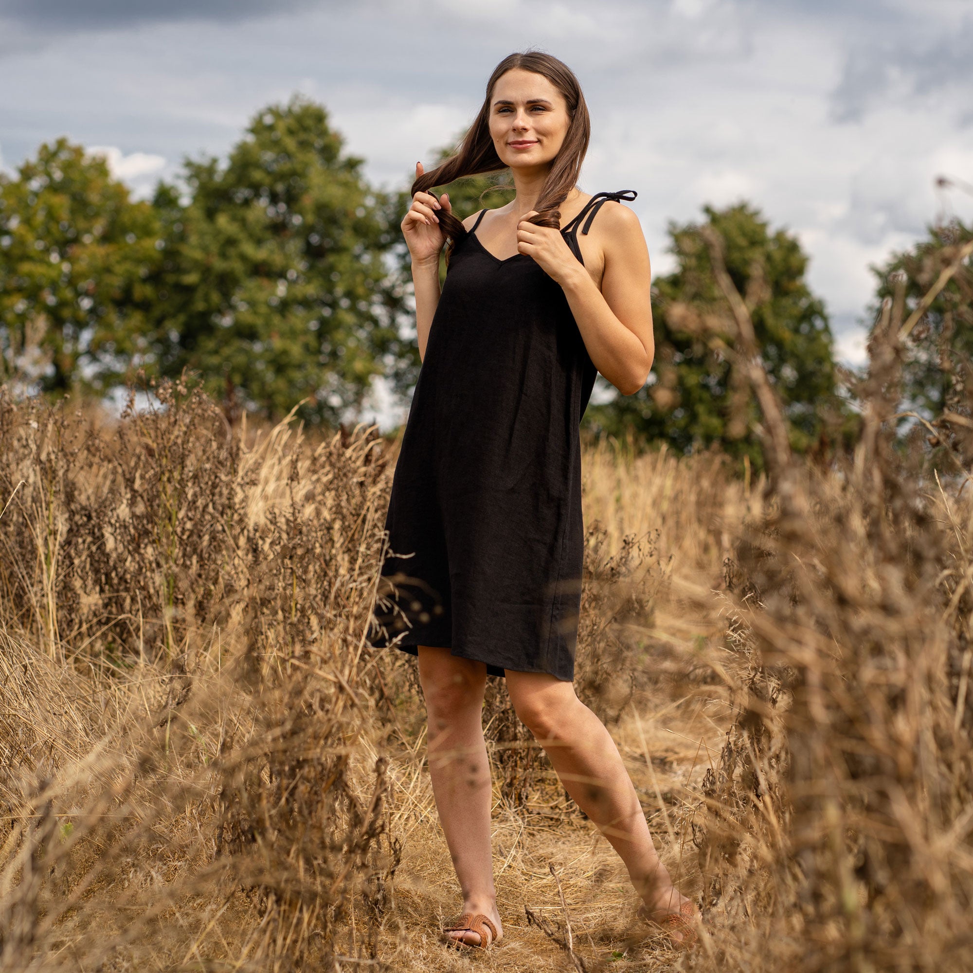 Woman standing outdoor and wearing a Liv slip dress made from linen in black color