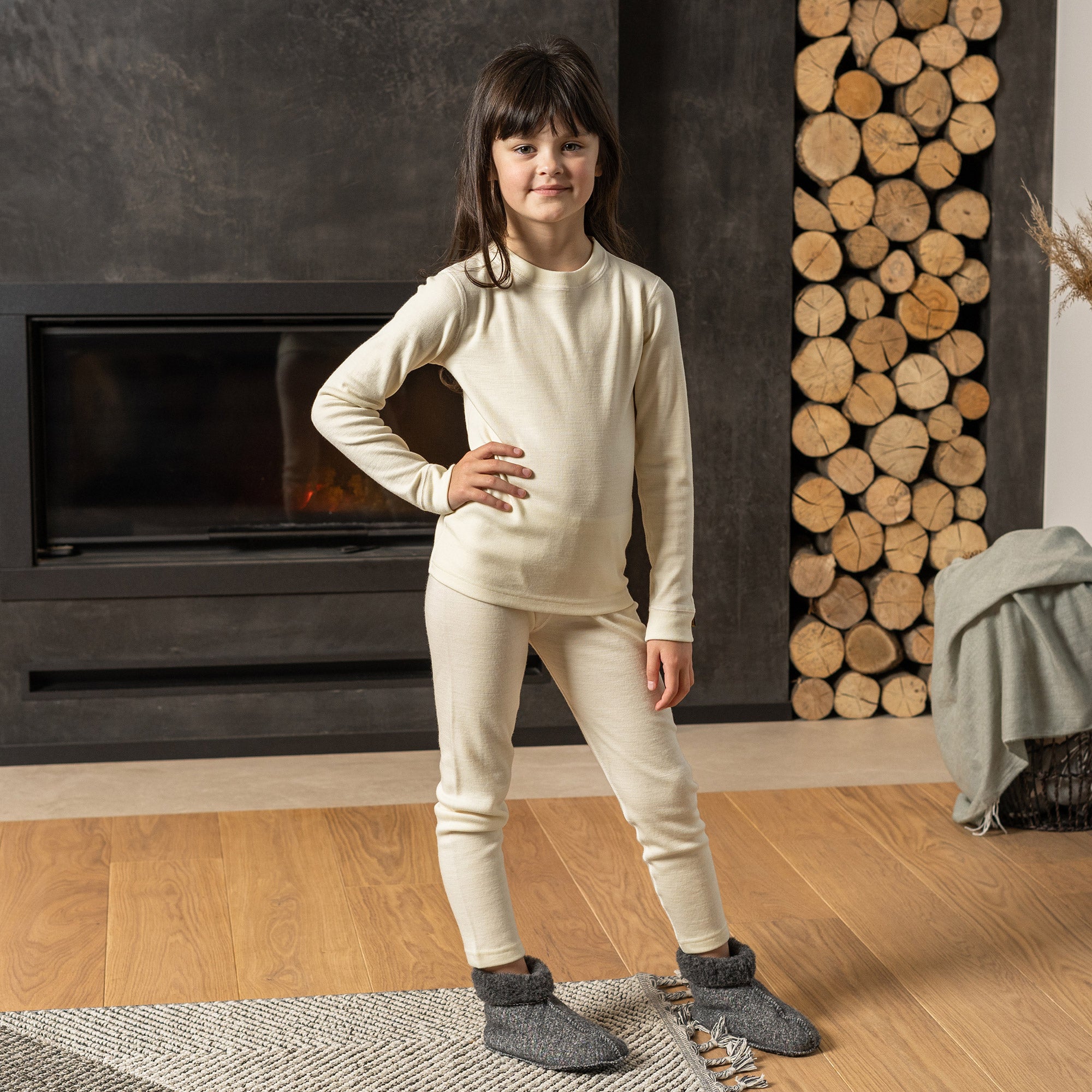 little girl in natural color matching merino thermal set jumping out of the bed