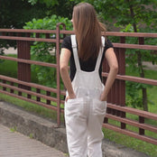 Young girl in a city street walking wearing pure white linen jumpsuit.
