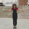 Beautiful woman with curly hair posing in the city wearing pure black linen jumpsuit Nicci, royal cherry merino wool top.