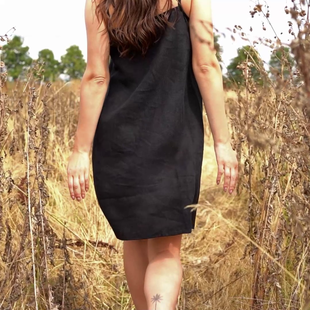 Woman walking through tall grass and wearing linen dress